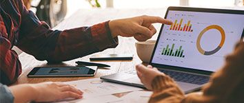 Person pointing at ad metrics on laptop screen